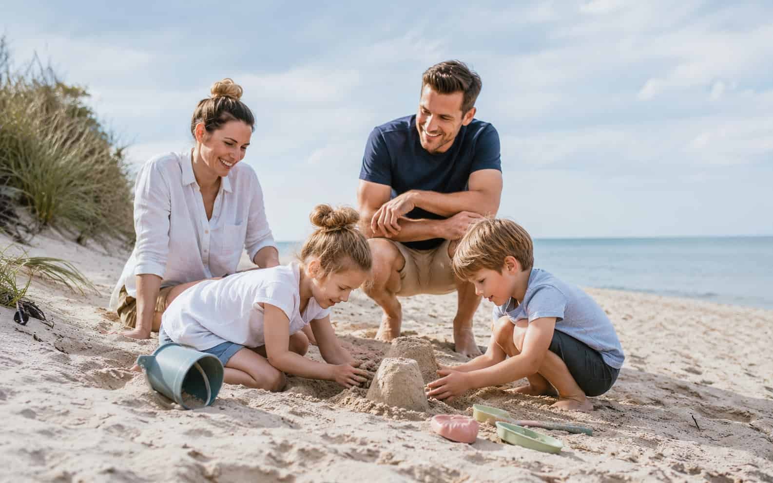 Kinder spielen an einem ruhigen Ostseestrand mit Familie im Hintergrund
